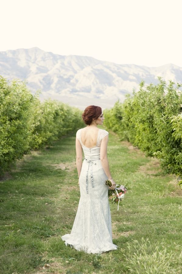 A white lace sheath wedding dress with a cutout back, a floral sash will highlight all your curves at its best