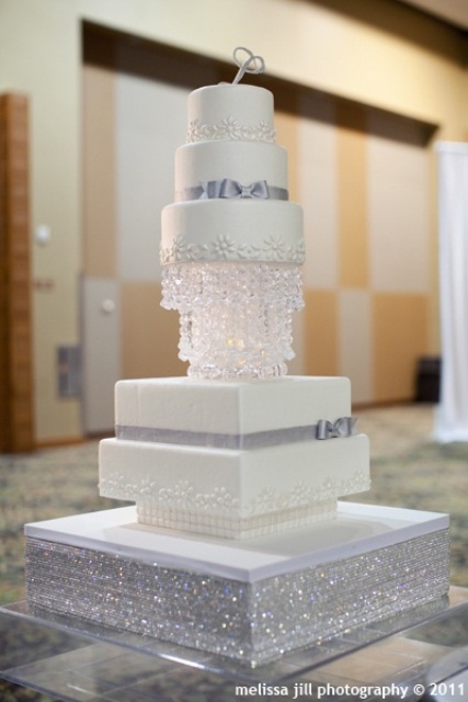 a glam and sparkly white and silver wedding cake with different tiers, glam decor and a rhinestone stand