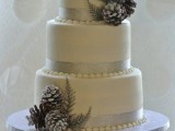 a white wedding cake with grey ribbons, snowy pinecones and greenery is a cool idea for a winter wedding