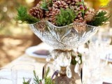 a refined winter wedding centerpiece of a crystal bowl, pinecones, ferns and berries is a beautiful and easy decoration