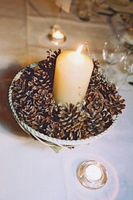 a wedding centerpiece of a bowl with pinecones and a pillar candle is an easy decoration idea to rock