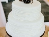 a white textural wedding cake topped with pinecones is a stylish option for a winter wedding