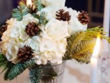 a winter wedding centerpiece of a glass vase, evergreens, white blooms and pinecones is amazing and easy to DIY