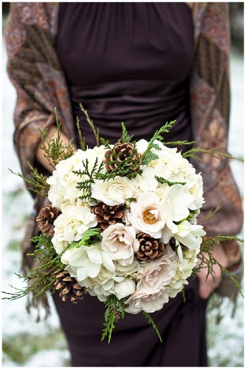 a winter wedding bouquet with white and blush blooms, ferns and pinecones is a bold and non-traditional idea