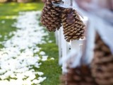 oversized pinecones on ribbons line up the aisle in a stylish way making it cooler and more natural, a great idea for a fall or winter celebration