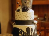 a black and white wedding cake with patterns, ribbons, sugar blooms and a bottle of champagne on top