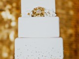 a white square wedding cake with gold glitter and beads, with white and gold sugar blooms is a very glam and cool idea