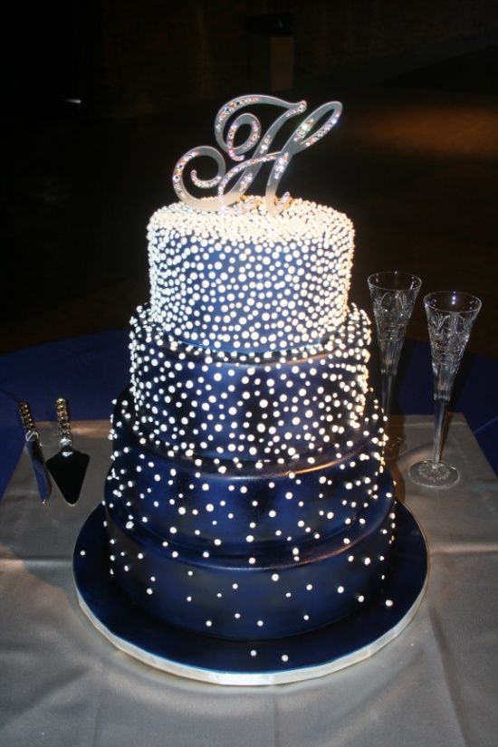 A navy wedding cake with white 3D polka dots and a shiny cake topper, a monogram for an elegant look