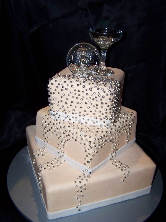 A tan square wedding cake with silver beads and champagne glasses on top is a chic and shiny idea