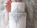 a white textural wedding cake heavily embellished with grey edible gems and beads is very refined and chic