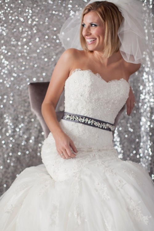a strapless lace embellished mermaid wedding dress with an embellished sash and a veil is very girlish and glam