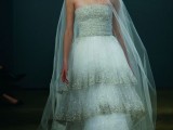 a strapless sheath wedding dress with a layered skirt with gold sparkles along the edge and a long veil is wow