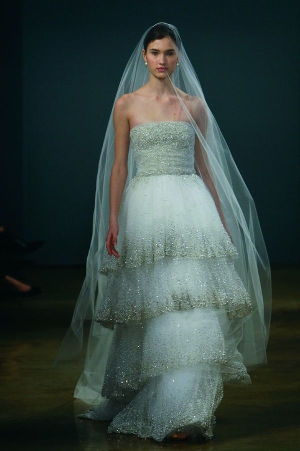 A strapless sheath wedding dress with a layered skirt with gold sparkles along the edge and a long veil is wow