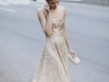 a strapless ivory and gold sequin A-line wedding dress with an ombre effect and a glam embellished clutch