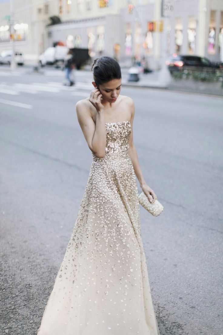 A strapless ivory and gold sequin A line wedding dress with an ombre effect and a glam embellished clutch