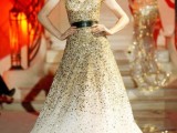 a strapless fully embellished gold sequin wedding dress with an ombre effect and a black leather belt is a bold statement
