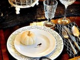 a stylish Halloween table setting done with black touches, printed plates, elegant glasses and a cage
