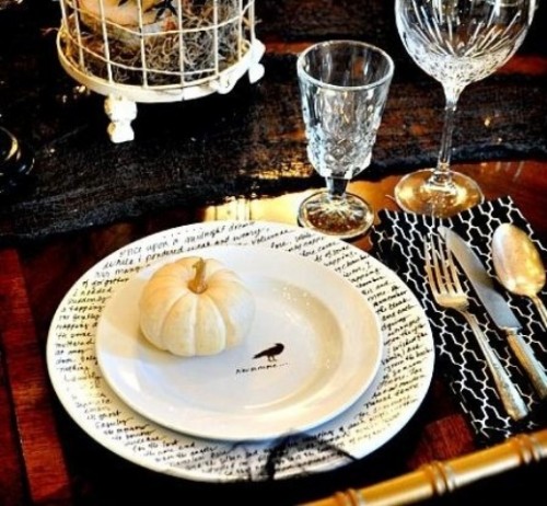 a stylish Halloween table setting done with black touches, printed plates, elegant glasses and a cage