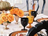 a bold Halloween wedding tablescape with orange blooms, glasses in black and orange, pumpkins and printed plates