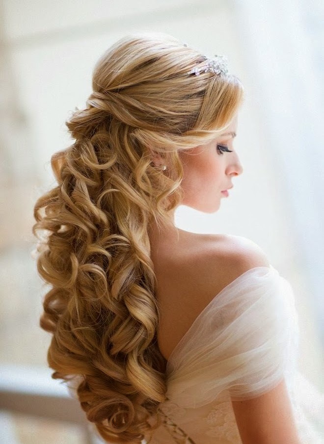 A sophisticated and refined wedding half updo with a volume on top and waves and curls down, with a chic rhinestone hairpiece is a chic idea for a refined bride