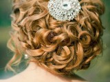 a gorgeous wavy and curly low updo with some waves down accented with a large rhinestone in the center is a fantastic idea to rock