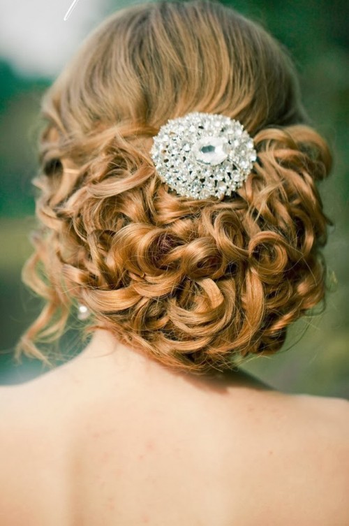 a gorgeous wavy and curly low updo with some waves down accented with a large rhinestone in the center is a fantastic idea to rock