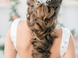 a long and voluminous twisted and wavy braid with some hair up, secured with a rhinestone hairpiece is a lovely idea for a refined and chic wedding