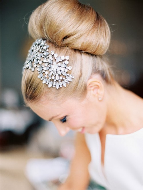 a classic top knot, a large one as the hair is long, accented with a bold rhinestone headpiece on top for a formal bridal look with a glam feel