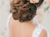 an exquisite low updo with twists and waves accented with a peachy bloom is a gorgeous idea for a formal bridal look in spring or summer
