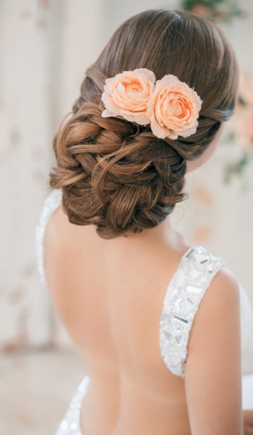 an exquisite low updo with twists and waves accented with a peachy bloom is a gorgeous idea for a formal bridal look in spring or summer