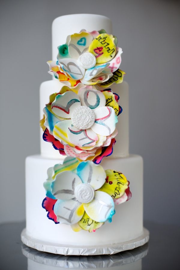 a white buttercream wedding cake with super colorful paper flowers is a gorgeous idea as these flowers are inspired by graffiti