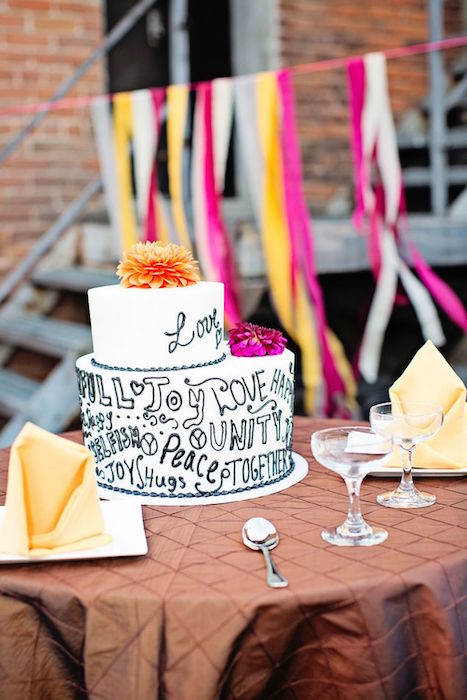 a stylish modern black and white cake with black graffiti, colorful blooms on top is a very cool and fresh idea to rock for a modern wedding