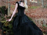 a black Victorian-inspired wedding dress with wide straps, a deep neckline, buttons and a tiered skirt for a Gothic bride