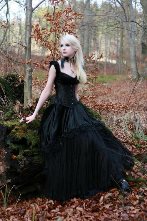 a black Victorian-inspired wedding dress with wide straps, a deep neckline, buttons and a tiered skirt for a Gothic bride
