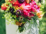 a super bold woodland wedding bouquet with hot pink, red and deep purple blooms, greenery and ferns is a statement for a summer or fall bride