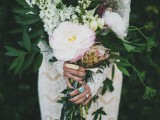 a large and dimensional wedding bouquet with greenery, white and pink blooms, herbs and long gold ribbons with tassels is wow