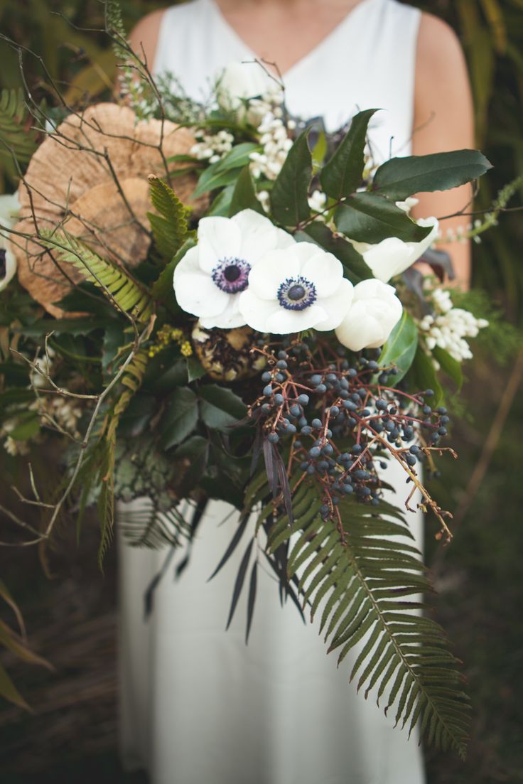 An eye catchy woodland wedding bouquet with white blooms, privet berries, foliage and twigs is a very catchy dimensional piece