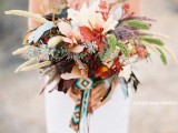 a bold boho forest wedding bouquet with various kinds of foliage, dried leaves and feathers and some boho woven ribbons plus no blooms
