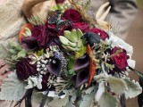 a dark woodland wedding bouquet of deep purple roses and callas, pale greenery, antlers, succulents and antlers for a fall woodland bride