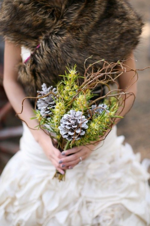 a winter woodland wedding bouquet of whitewashed oinecones, greenery and twigs is great for a winter woodland wedding