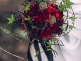 a bold deep red wedding bouquet of blooms, berries and foliage, usual and dark, with black ribbons for a fall bride