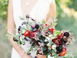 a refined fall wedding bouquet of red and deep purple blooms, greenery and some berries is a pretty and cool idea for a fall woodland wedding