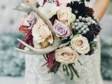 a woodland wedding bouquet with blush and lilac blooms, dark burgundy flowers, antlers and berries is ideal for the fall