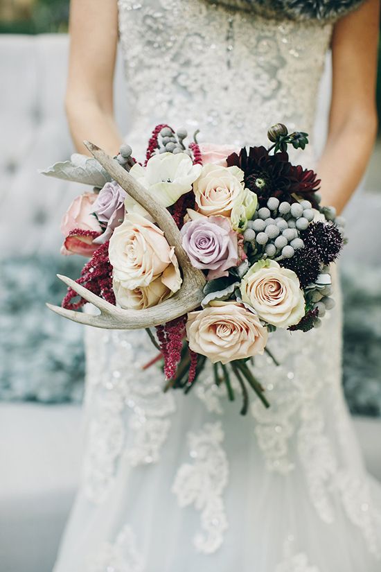 A woodland wedding bouquet with blush and lilac blooms, dark burgundy flowers, antlers and berries is ideal for the fall