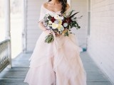 a glam and romantic blush strapless wedding dress with a layered skirt with ruffles and a coverup