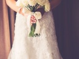 a strapless lace embellished wedding dress and a classic white rose bouquet for a stylish and timeless barn bridal look