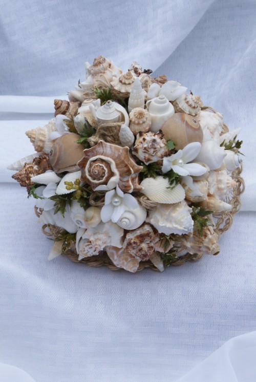 a rough wedding bouquet of seashells, pearls, greenery, white fabric blooms shaped as a ball