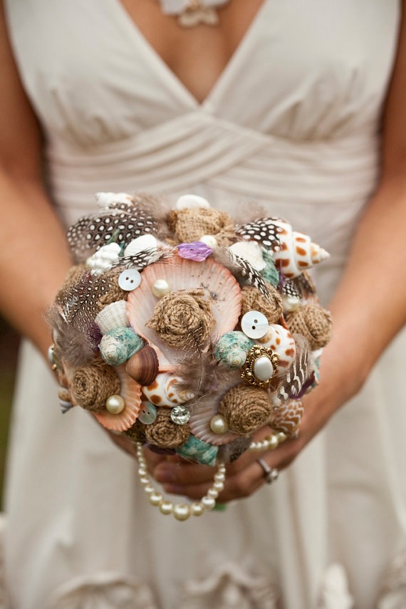 A bright and non typical wedding bouquet composed of buttons, pearls, seashells and feathers