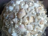 a sparkling beach wedding bouquet of neutral seashells, pearls and starfish brooches plus a fringe wrap