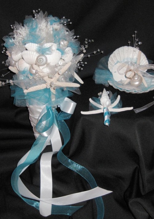 a blue and white wedding bouquet made of seashells, beads and farbic flowers plus ribbons